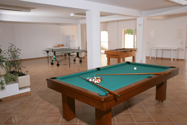 A recreation room featuring a pool table, table tennis, and foosball setup with ample space.